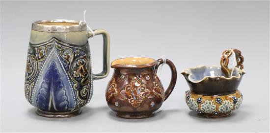 Two Doulton Lambeth milk jugs, c.1900 one with and a similar foliate design mug, dated 1883, with silver mounted rim, signed EBL?, H. 8